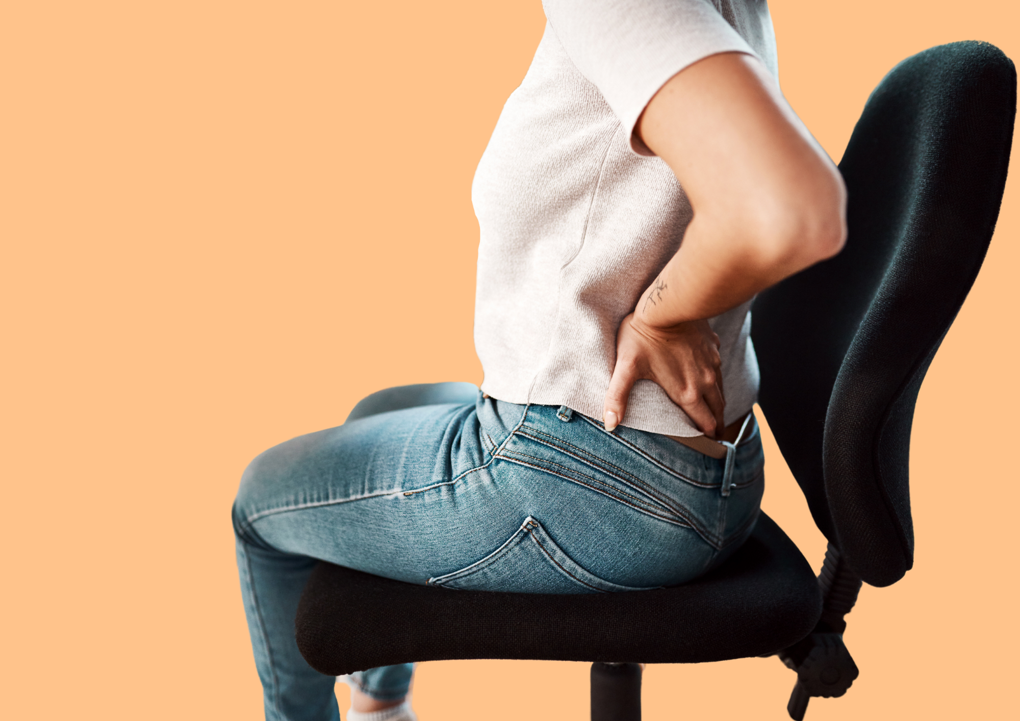 Woman sitting on chair, holding onto her low back in pain.