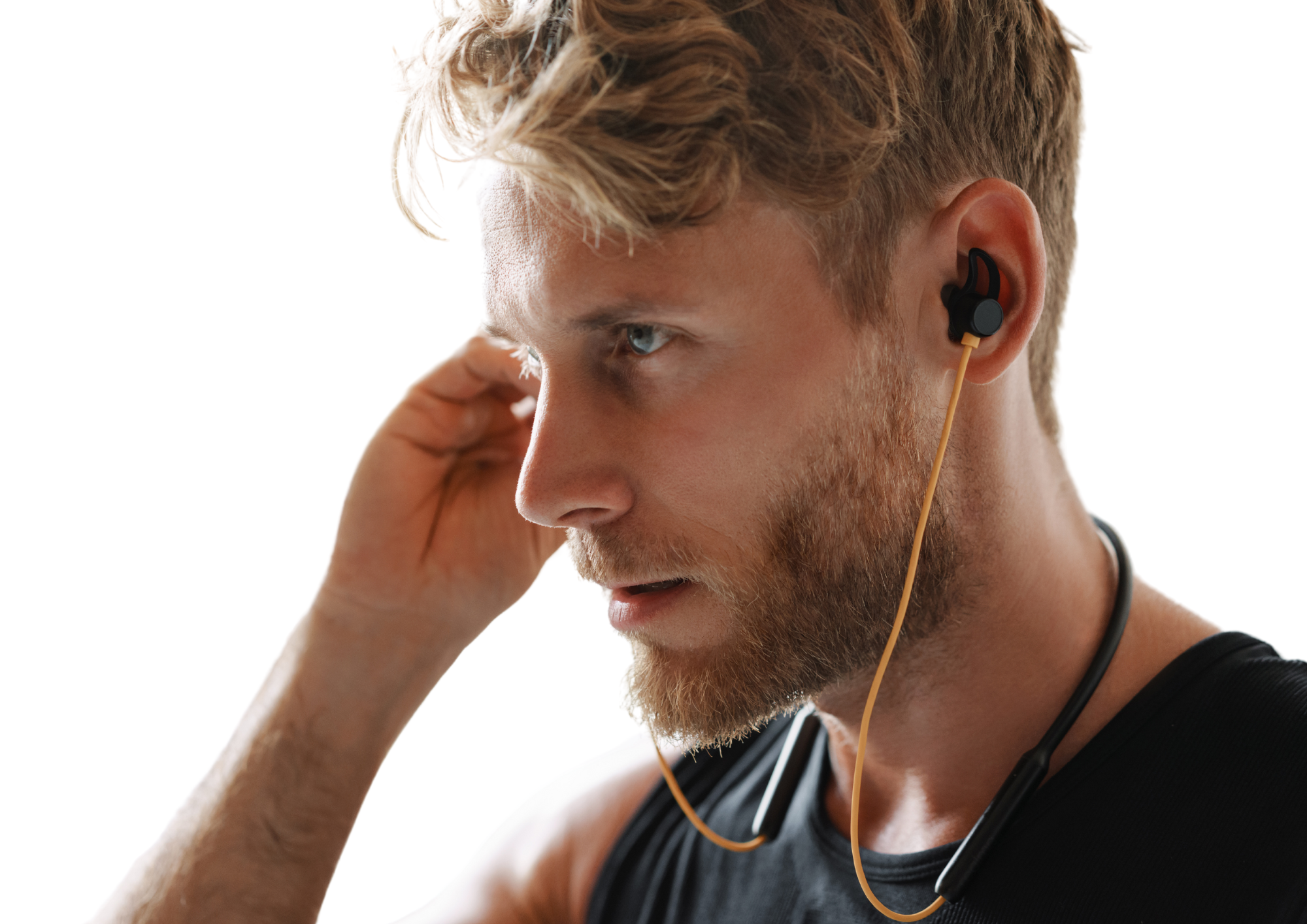 Junger Mann hört Musik auf Kopfhörern, konzentriert sich auf bevorstehendes Training. Weisser Hintergrund.