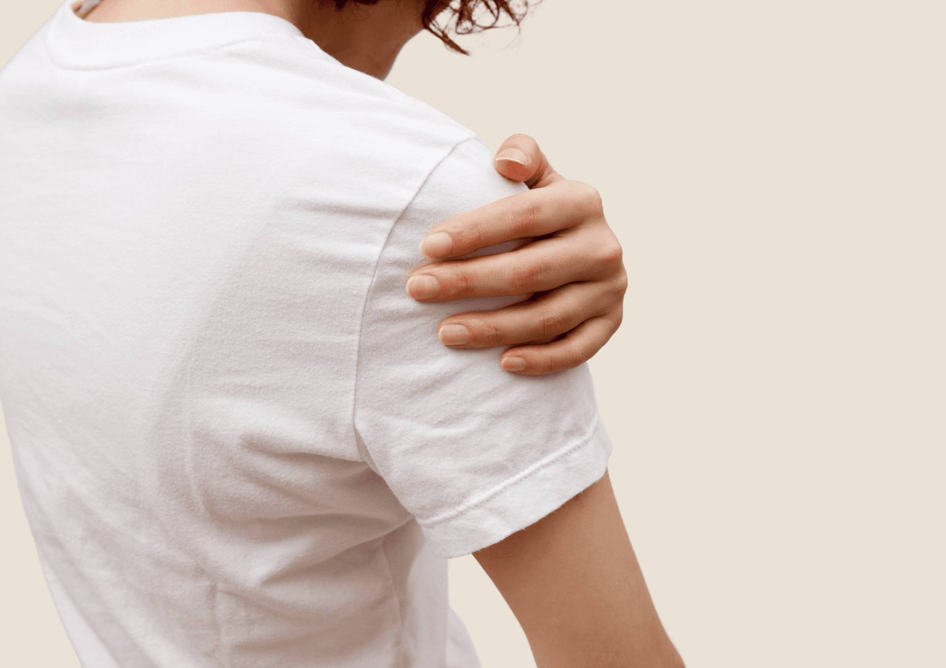 Person in weissem T-Shirt fasst sich an die schmerzende Schulter.