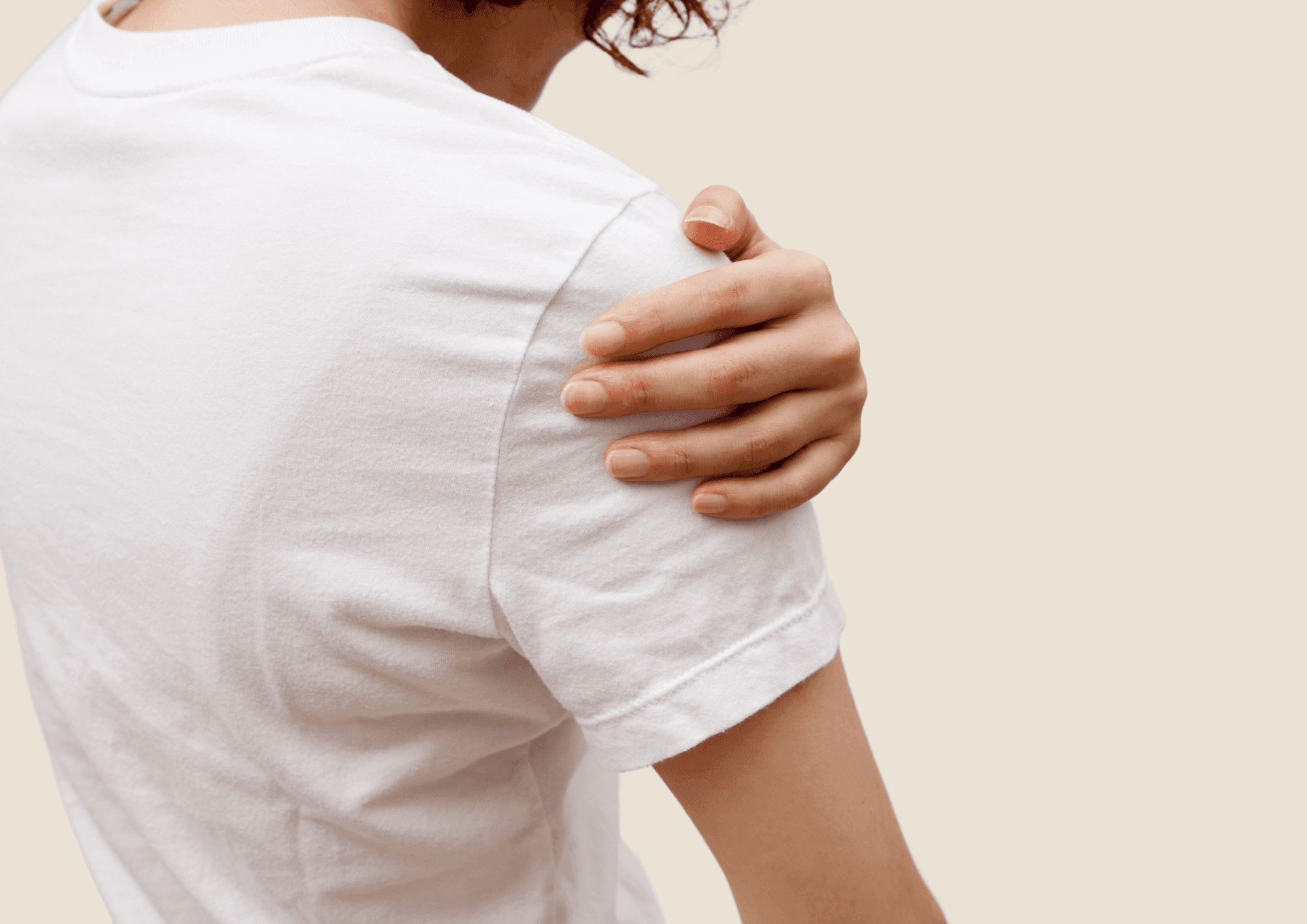 Person in weissem T-Shirt fasst sich an die schmerzende Schulter.